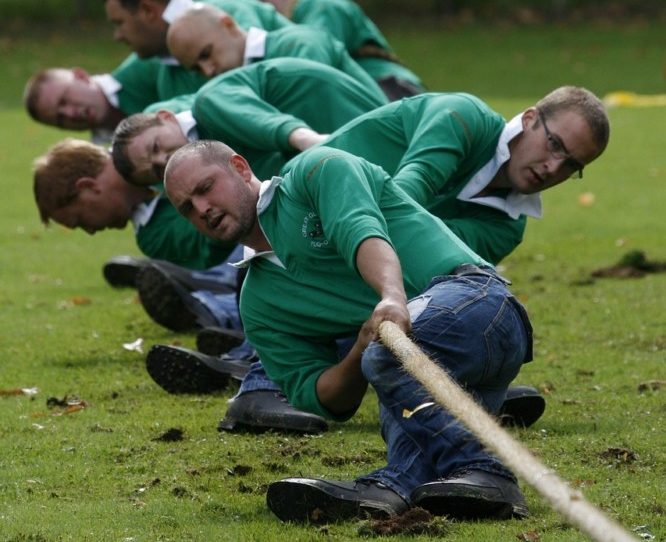 Rasenfläche mit Sportteam aus Männern, das am Seil zieht
